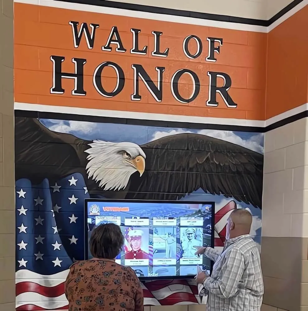 Visitors interacting with wall of honor digital display showing recognition profiles Interactive digital display with visitors